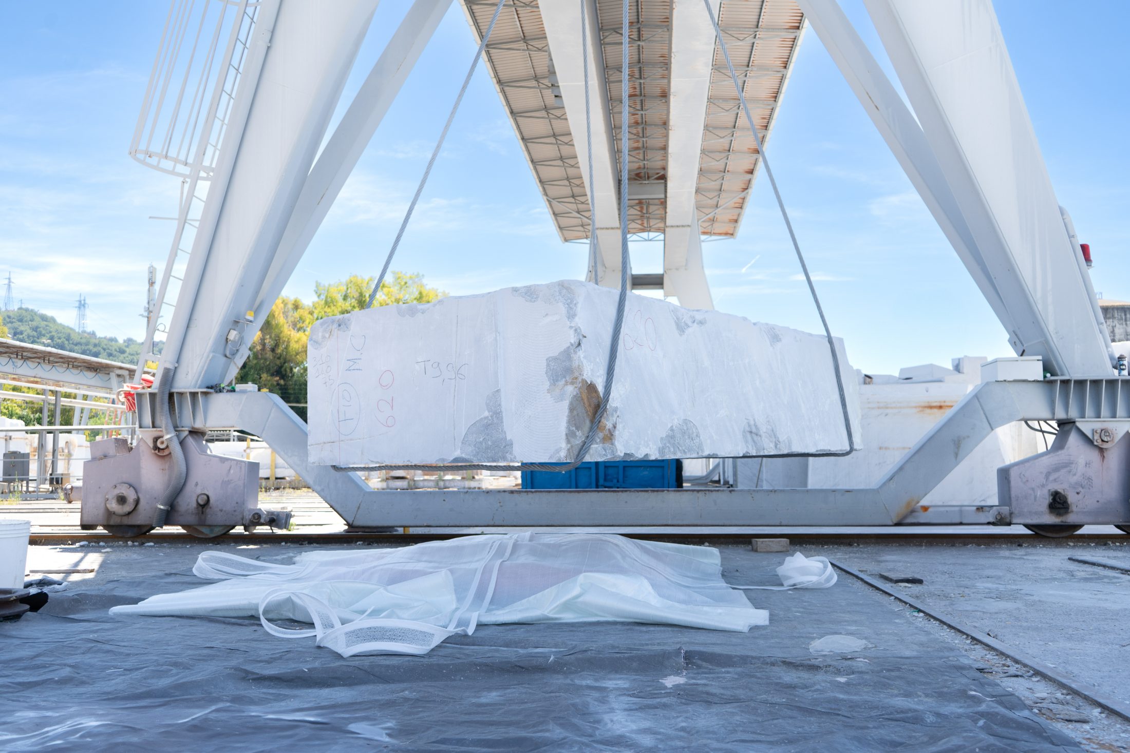 Blocco di marmo grezzo sollevato dal carroponte, prima del trattamento